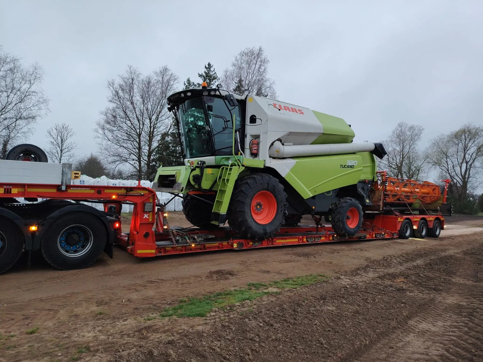 Kombajn zbożowy Claas wraz z hederem na 3-osiowej naczepie Tiefbett Gonera Transport
